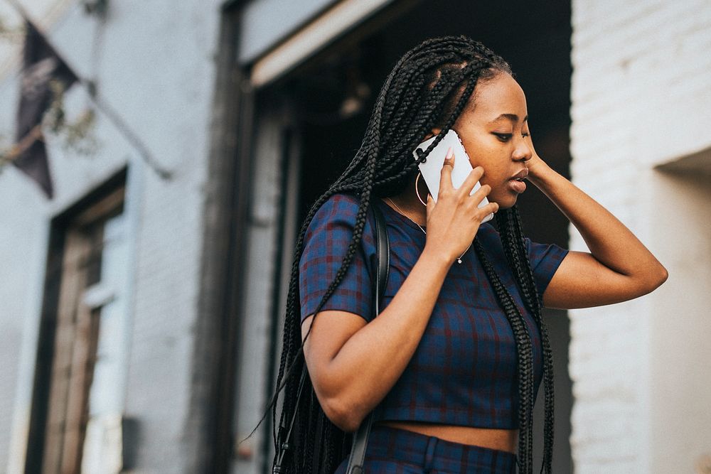 Black woman talking on the phone while walking on the streets