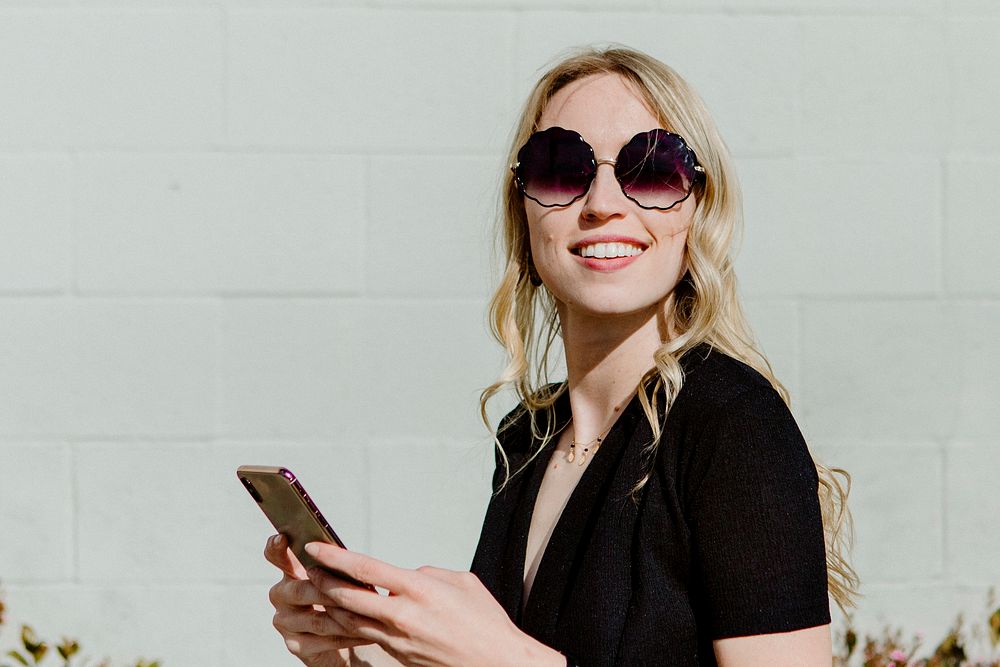 Cheerful woman with  a sunglasses texting on her phone