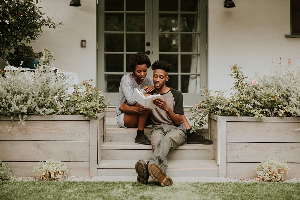 Cute black couple reading a book together in a garden