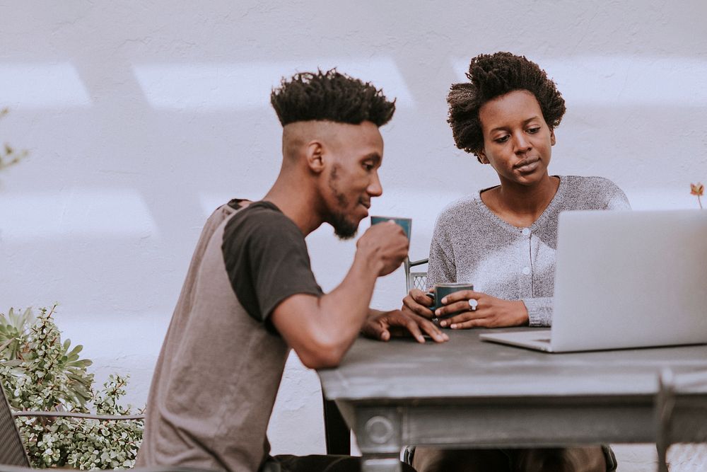 Black people drinking coffee and working on a laptop in the garden