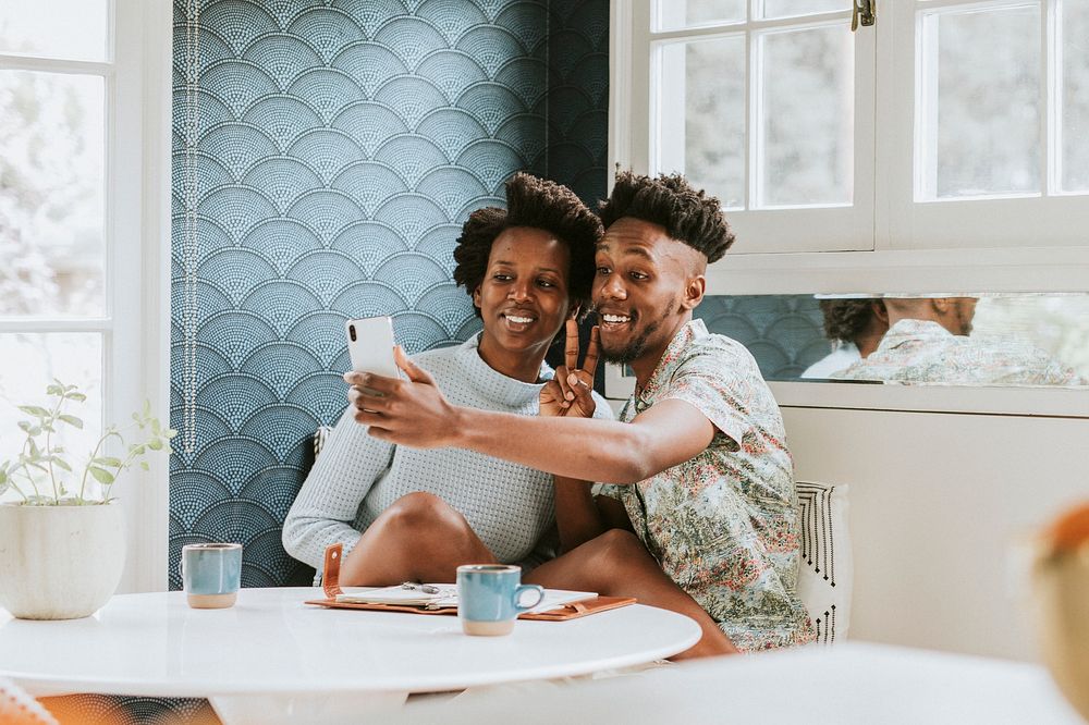 Happy black couple taking a selfie at home with a mobile