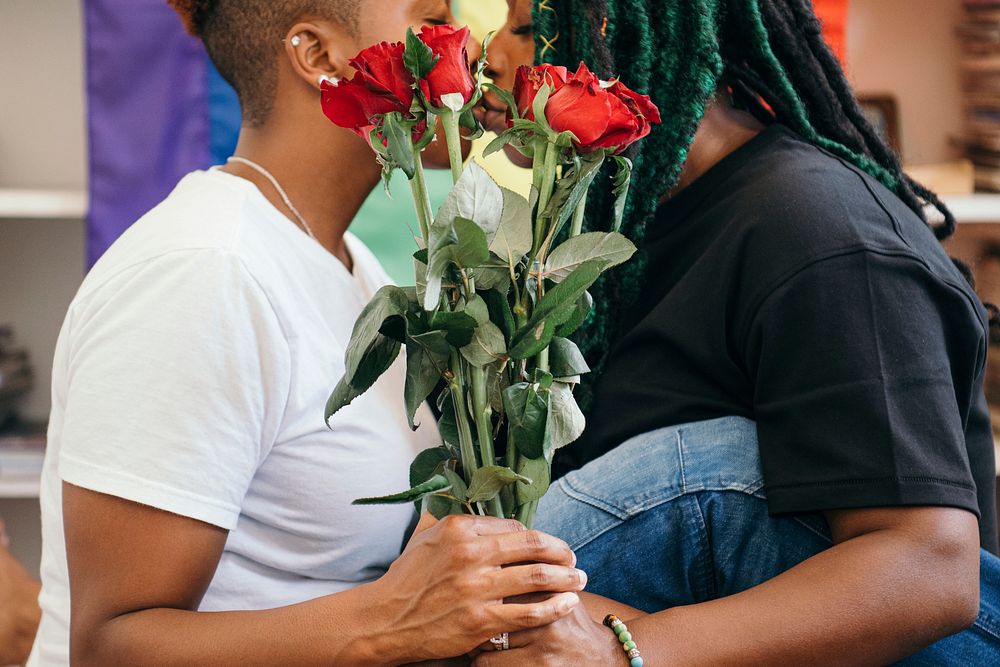 Happy lesbian couple with roses and a colorful flag