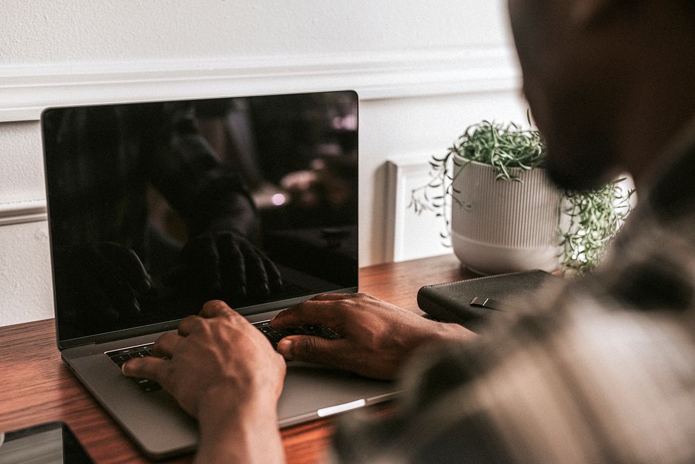 Black male blogger typing on a laptop