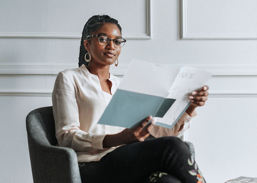Happy black woman reading a unique magazine