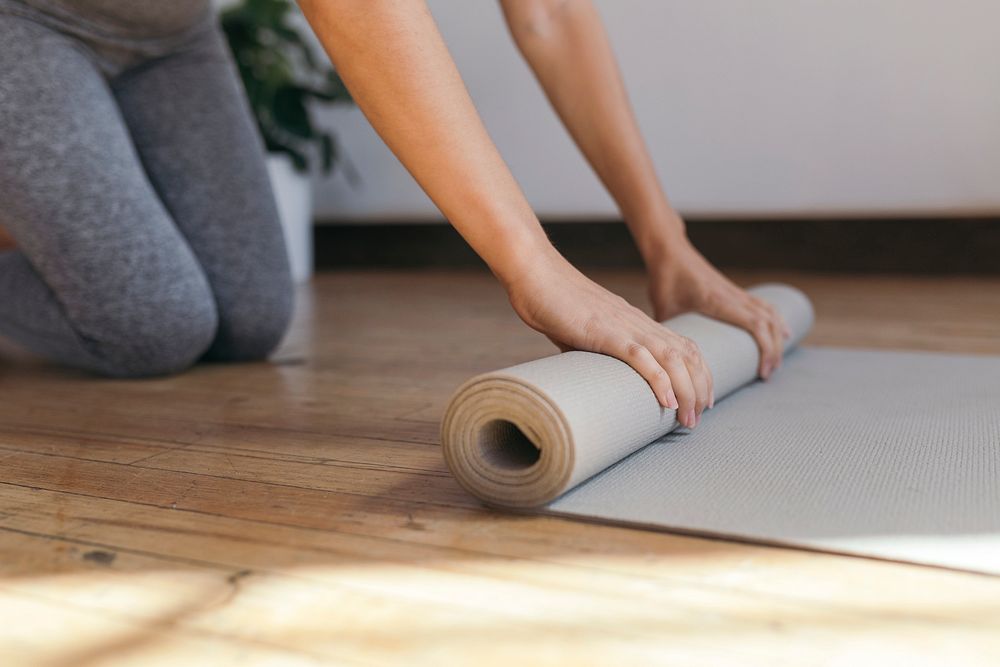 Sporty woman rolling a yoga mat