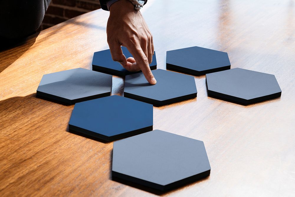 Hands pointing to connected hexagon cut out paper
