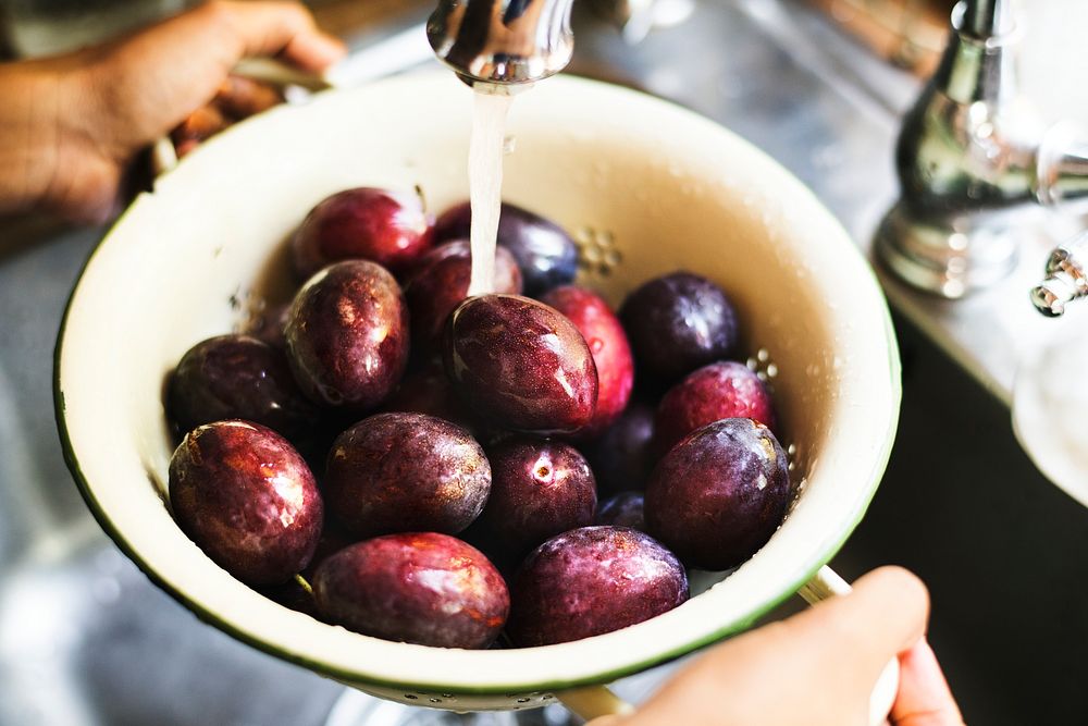 Organic plums being washed under running water food photography recipe idea