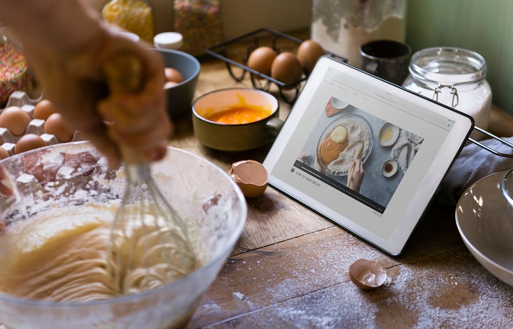 Woman whisking while looking at a recipe on a tablet