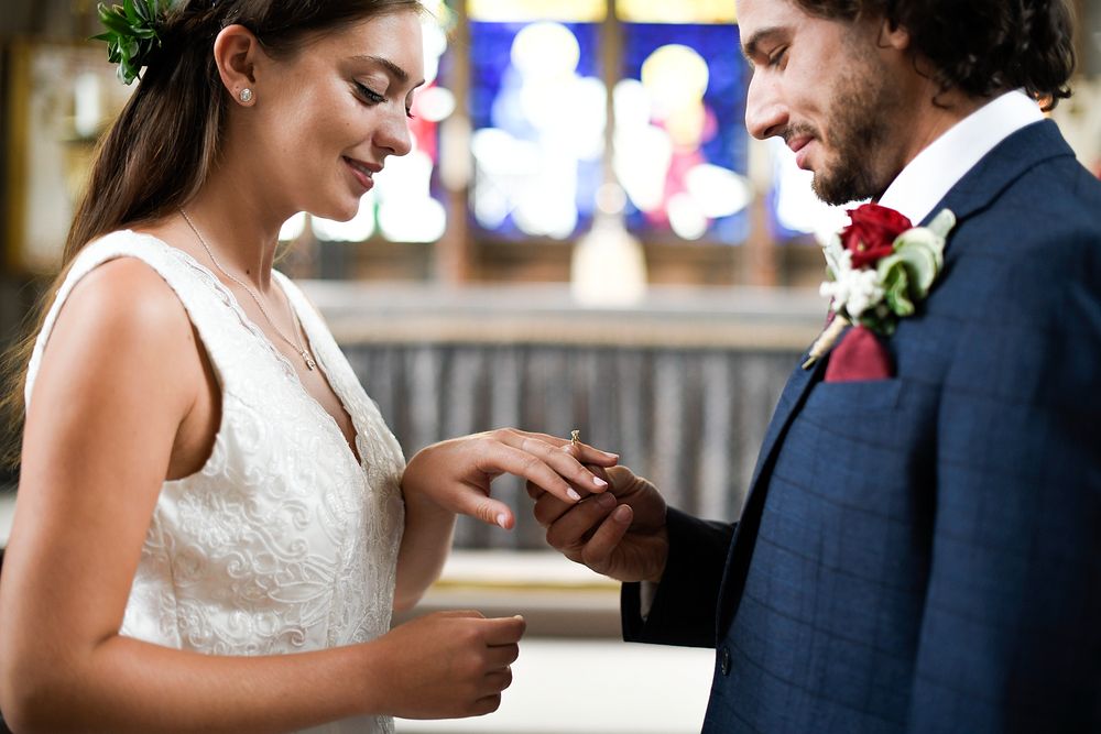 Groom putting on the wedding ring on his bride