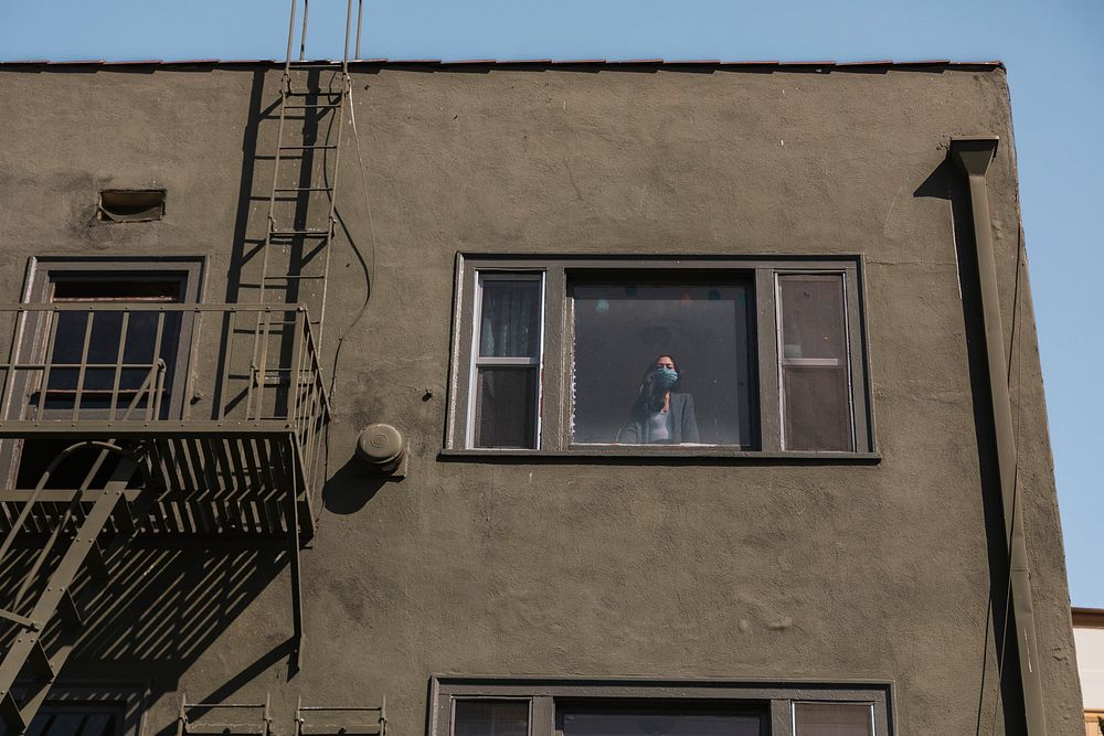 Woman looking out the window of her downtown LA apartment during the covid-19 pandemic