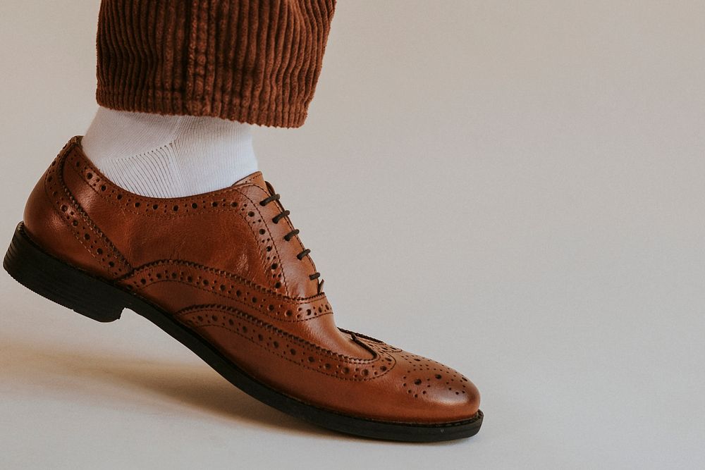 Men's leg in brown leather shoes