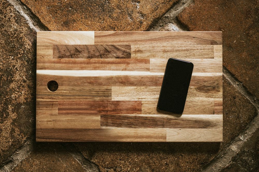 Mobile phone mockup on wooden cutting board flatlay
