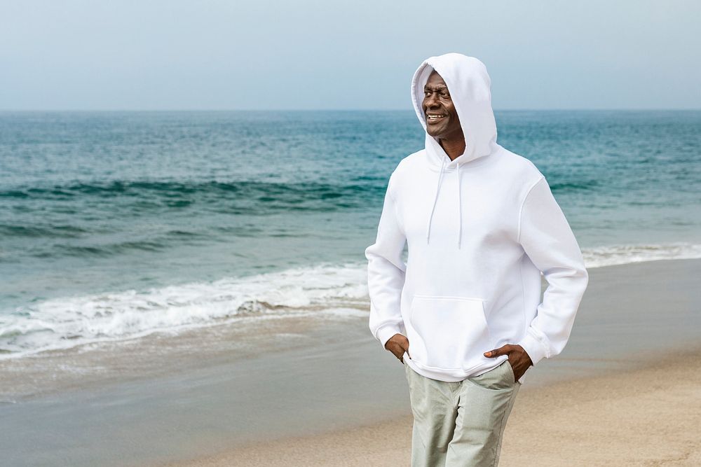 Cool African American man in white hoodie at a beach winter shoot