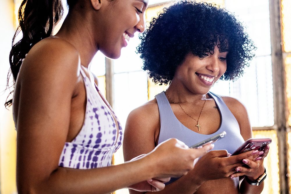 Cheerful sporty women checking their phones