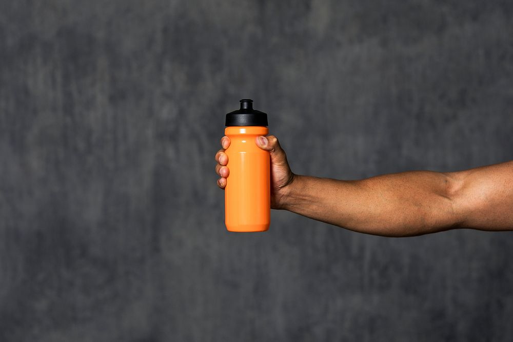 Muscular man holding an orange water bottle