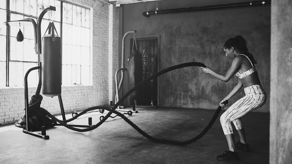 Sportive woman working out on the battle ropes