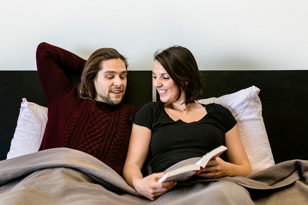 Sweet and loving couple reading together in bed