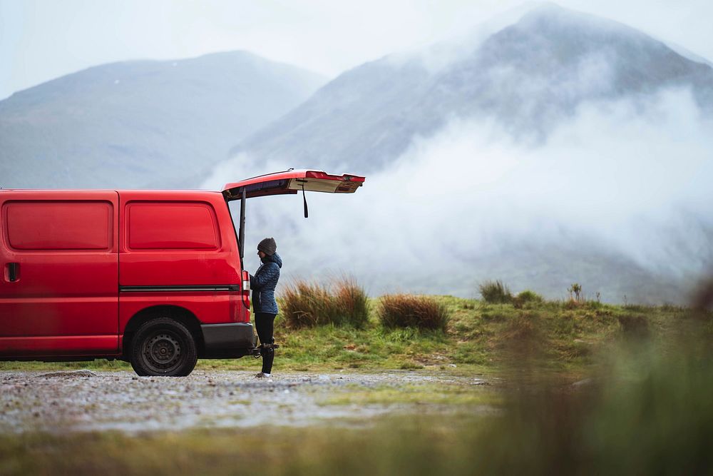 Woman standing by the red van in the highlands