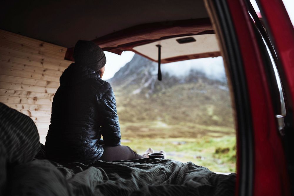 Woman sitting in her campervan looking at the mountains