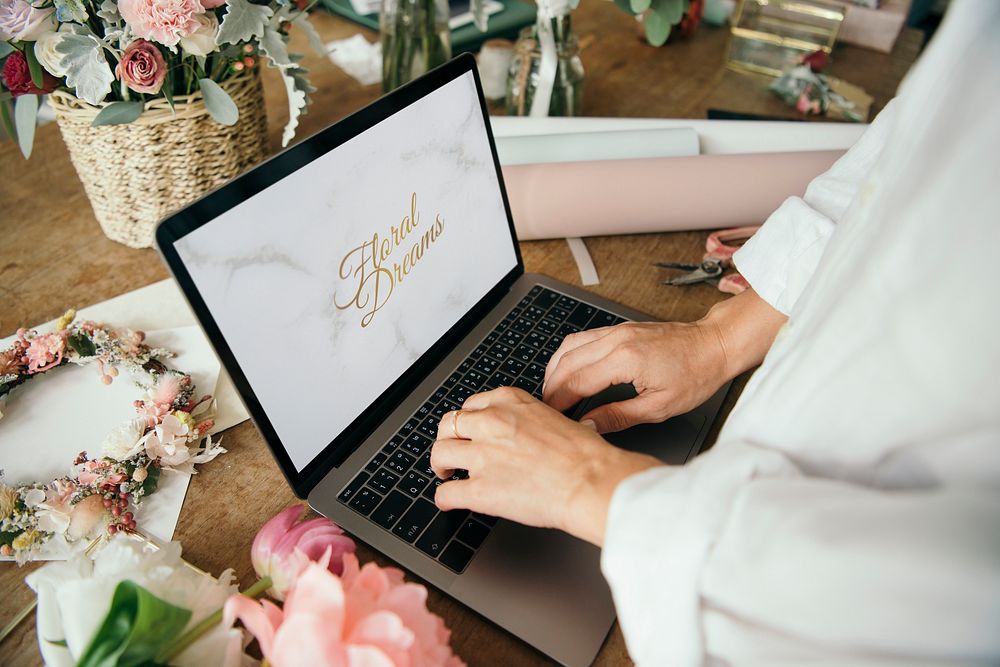 Florist creating designs on her laptop in a flower shop