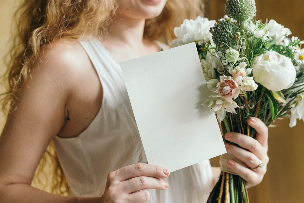 Woman holding a bouquet of white flowers with a card