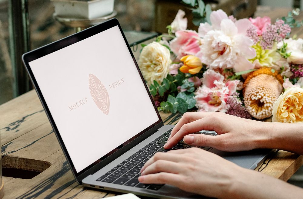 Florist creating designs on her laptop in a flower shop