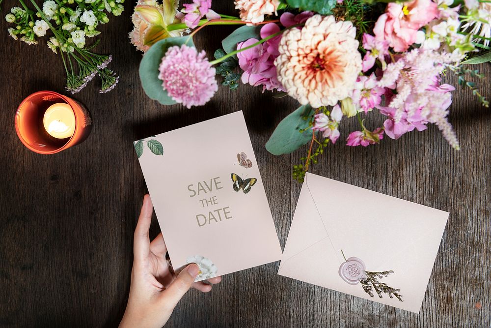 Woman holding a save the date card by a bouquet of flowers
