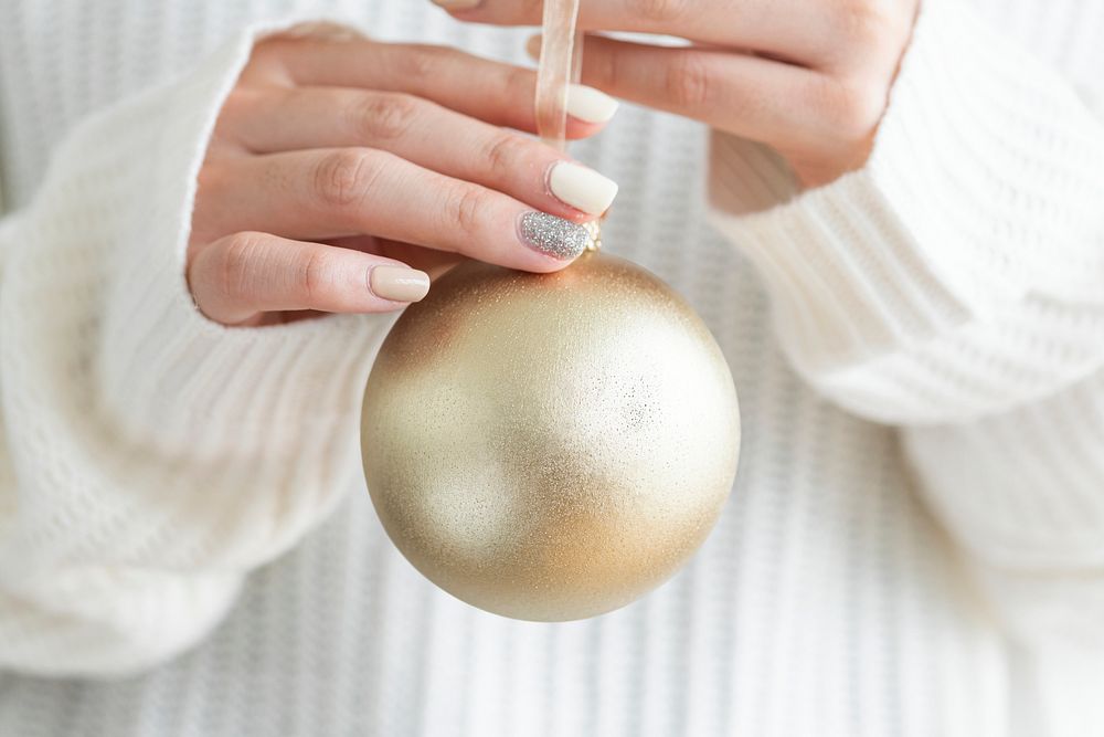 Woman in a white sweater holding a gold bauble