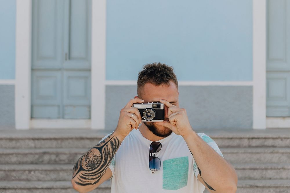 Tattooed man capturing a picture with his analog camear
