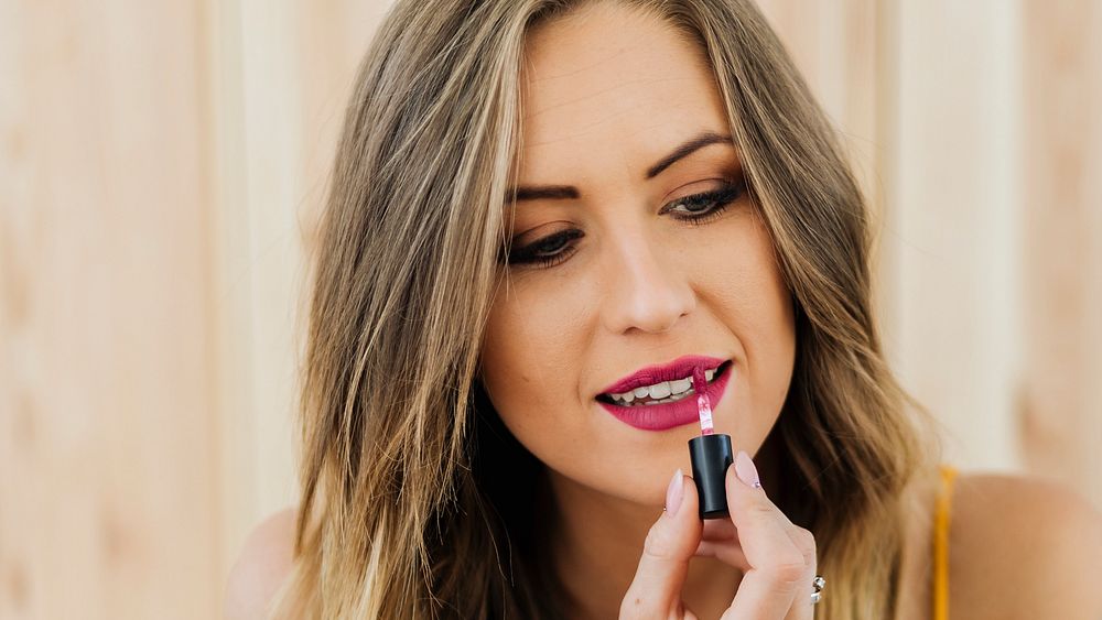 Blond beauty blogger applying liquid lipstick