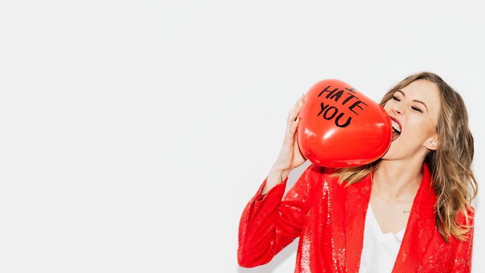 Woman in red jacket biting a red balloon