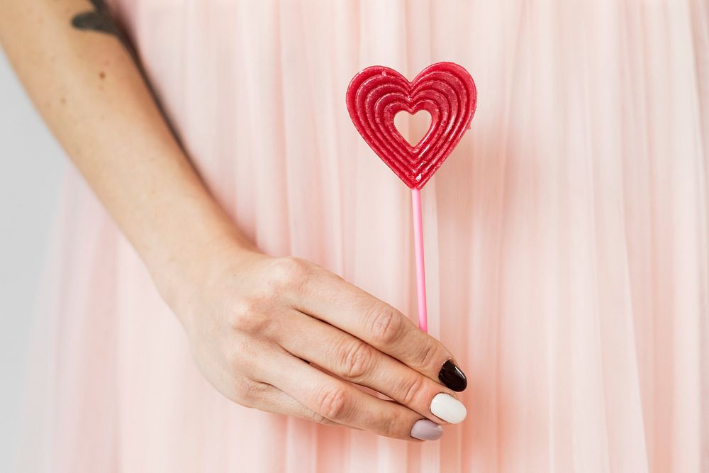 Woman holding a red heart on a stick  