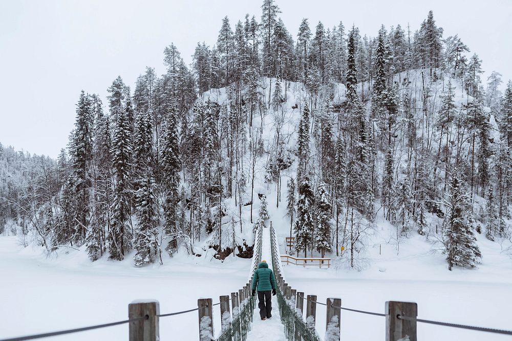 Woman crossing a suspension bridge in a snowy Oulanka National Park, Finland
