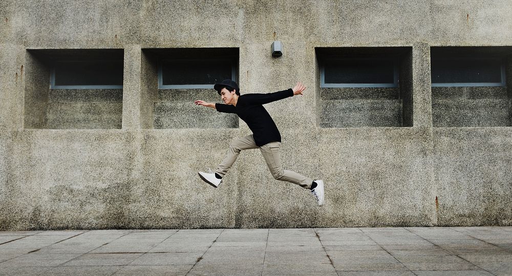Carefree man jumping mid-air, city photo