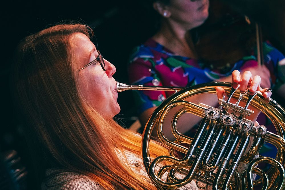 Woman playing French horn, October 15, 2019, UK. Original public domain image from Flickr