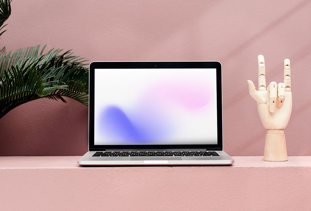 Laptop, hand mannequin, pink wall, tropical leaf