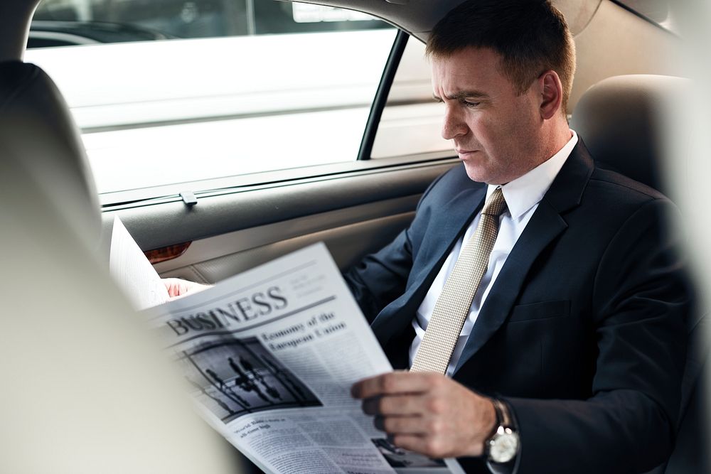 Businessman reading newspaper in  car