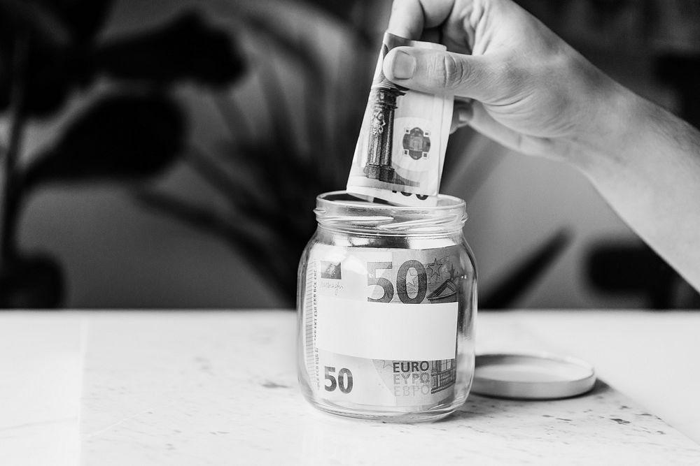 Saving money in jar, black and white photo