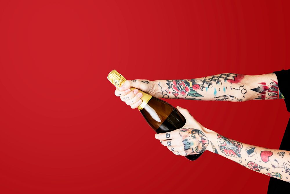 Tattooed hands popping a champagne