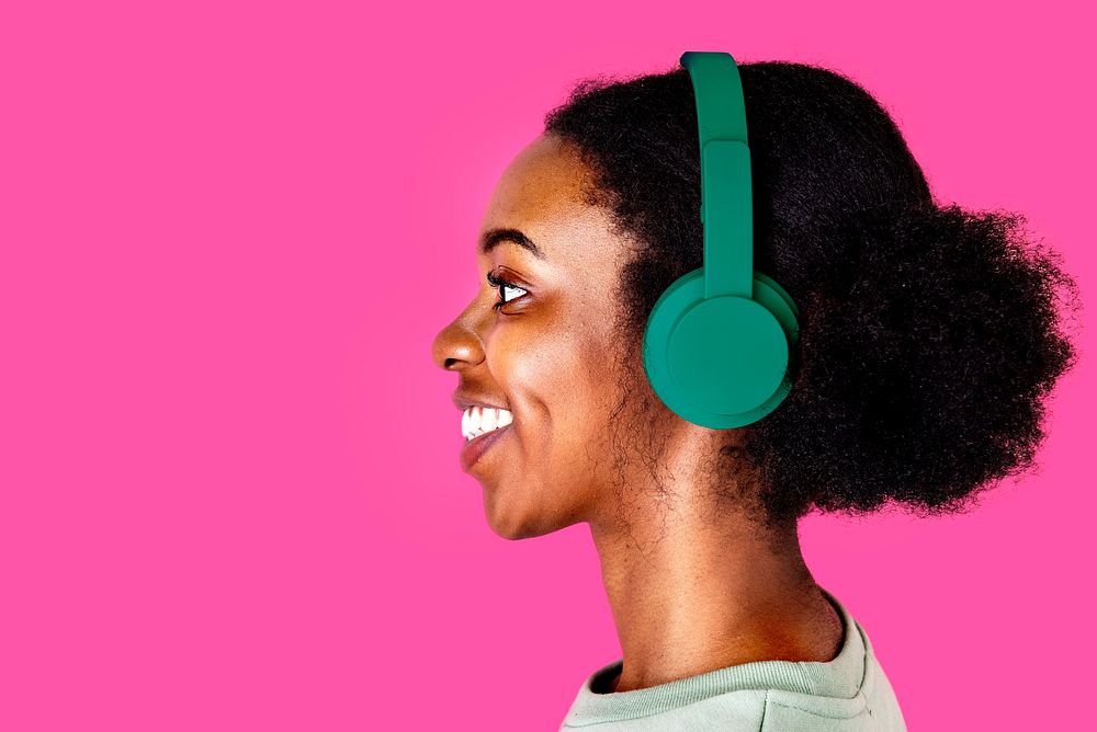 Happy woman listening to music, pink background