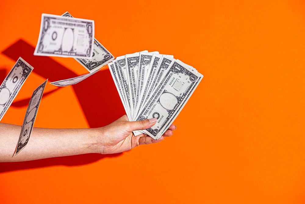 Hand holding cash, orange background