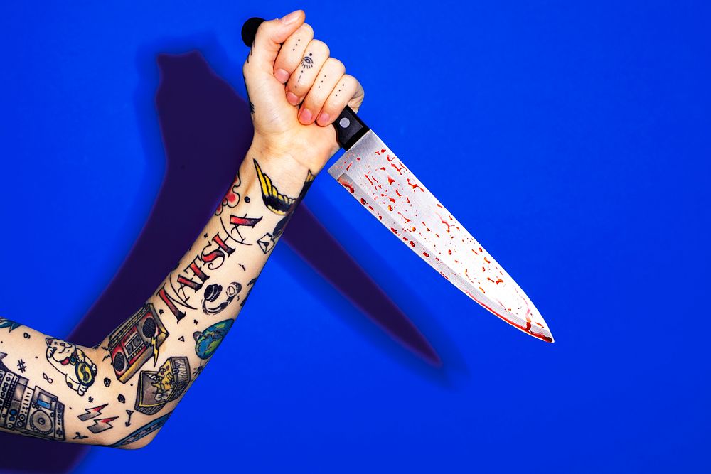 Tattooed hand holding a knife