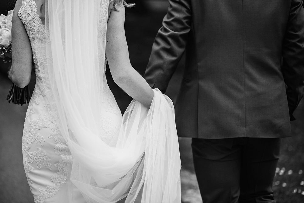 Wedding ceremony, bride & groom holding hands, black & white photo