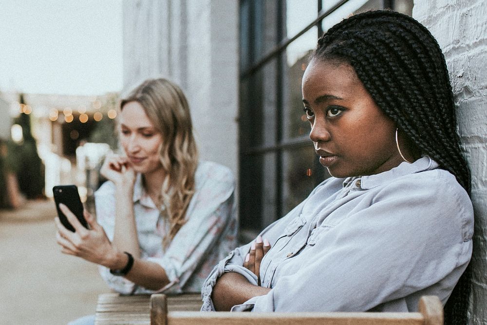 Black woman getting bored of her blond friend keep taking a selfie