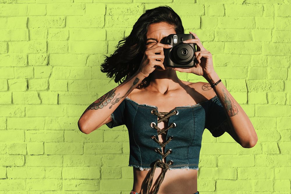 Tattooed woman holding instant camera