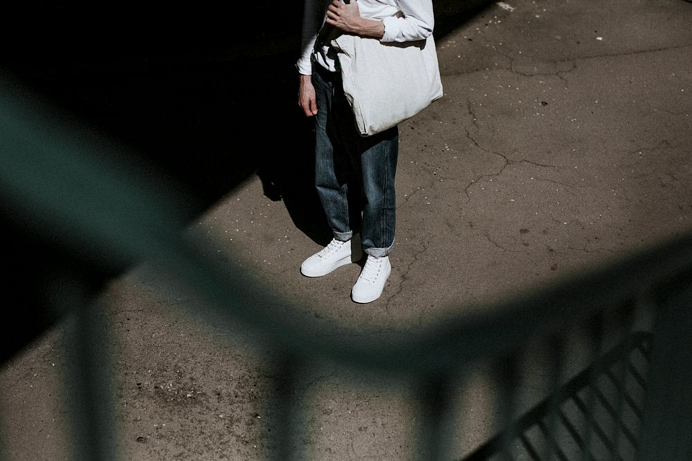 Man in jeans, white sneakers and canvas tote bag