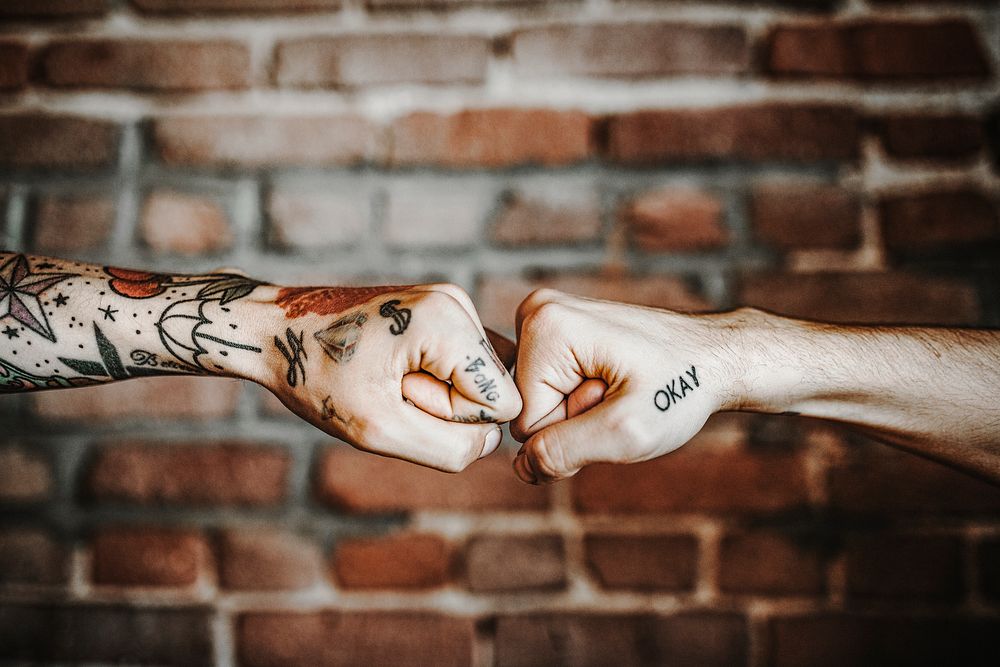 Tattooed hands doing fist bump