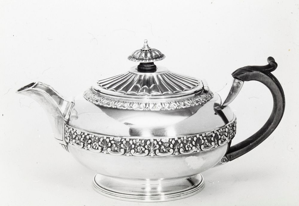 teapot, round, decorated at top and around the middle with a band of strap mount work in leaf and grape design; the spout is…
