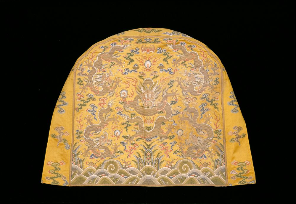 Shaped throne-back cover of imperial yellow satin brocade. In a field with loosely-drawn clouds and a bat, five five-clawed…