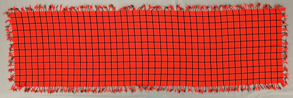 bright red-orange with plaid design in white, green and black; twisted fringe on all four sides. Original from the…